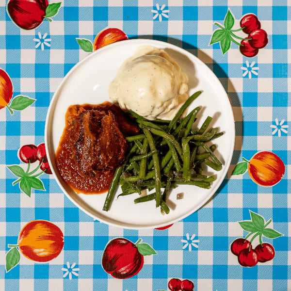 Doo-Dah Diner's meatloaf with mashed potatoes and green beans on a checkered tablecloth.