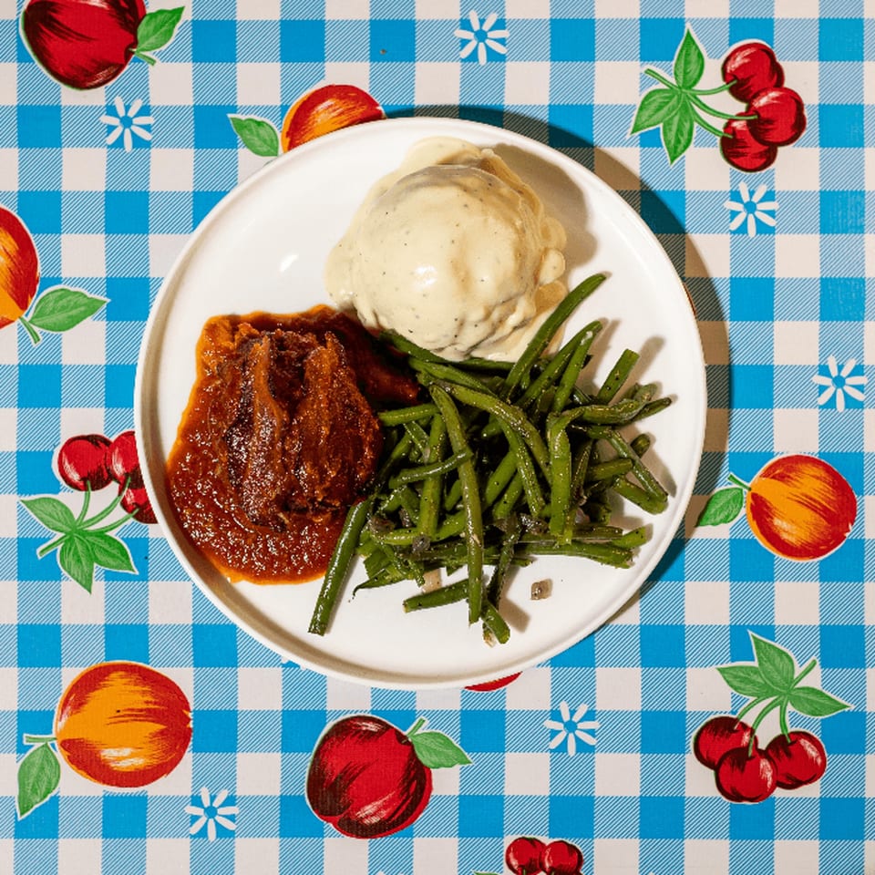 Doo-Dah Diner's meatloaf with mashed potatoes and green beans on a checkered tablecloth.