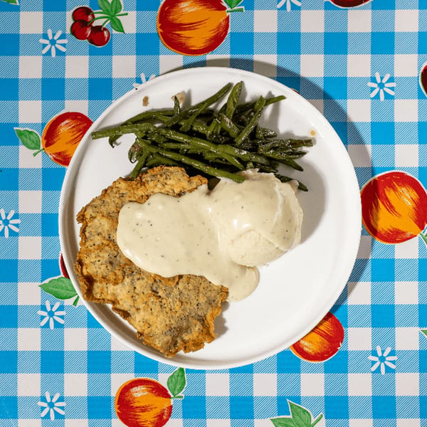 Doo-Dah Diner's chicken fried steak with gravy, mashed potatoes, and green beans on a checkered tablecloth.