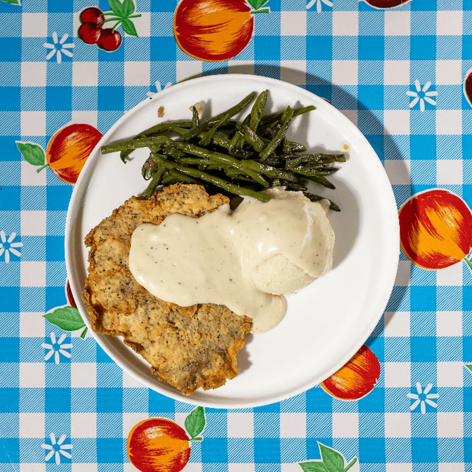 Doo-Dah Diner's chicken fried steak with gravy, mashed potatoes, and green beans on a checkered tablecloth.